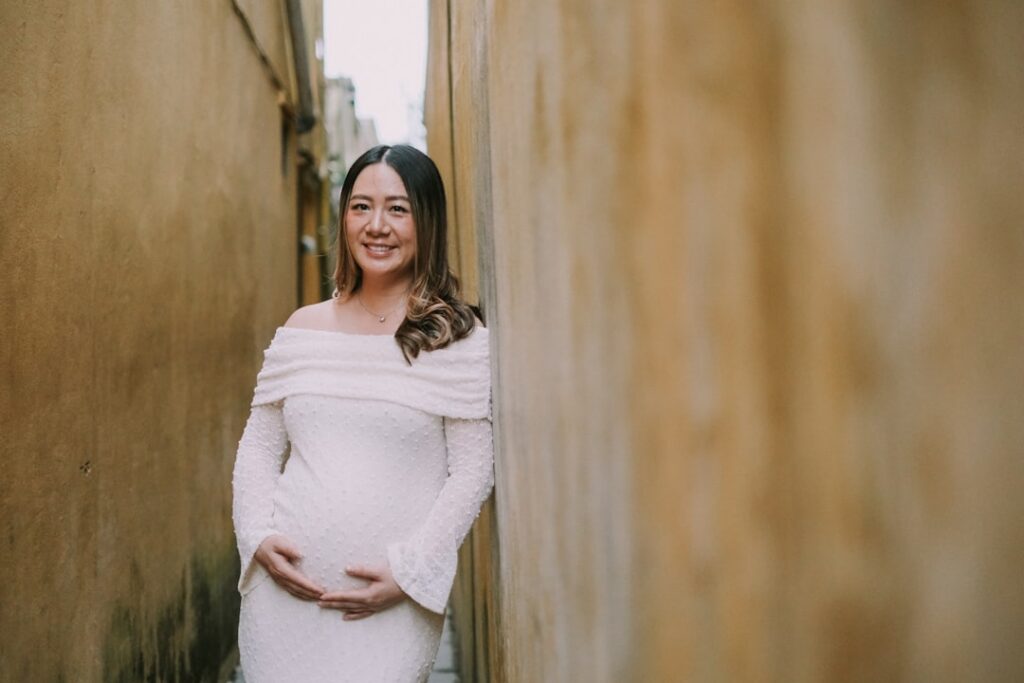 Pregnant woman in white dress holding belly