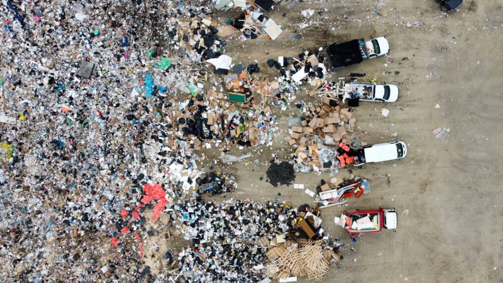 Aerial view of a landfill with scattered trash and vehicles.