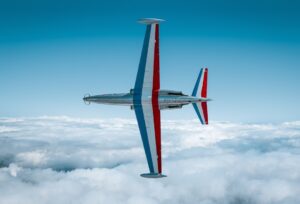 A jet airplane flies above clouds against blue sky