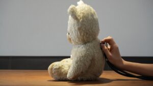 Hand using stethoscope on a teddy bear's back