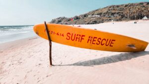 a surfboard leaning up against a pole on a beach